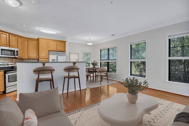 Una cocina moderna con gabinetes de madera y un comedor con mesa y sillas. - The Cosmopolitan at Lorton Station