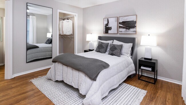 Relájese en un acogedor dormitorio con pisos estilo madera, iluminación suave y un amplio vestidor. - The Enclave at Huntington Woods