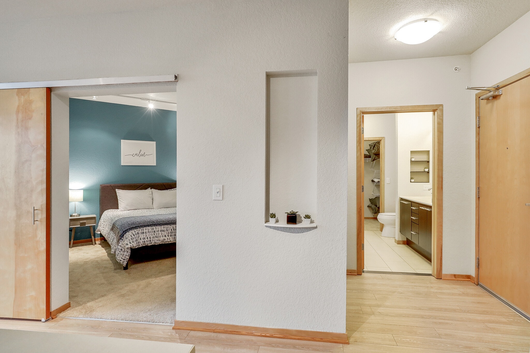 View into a bedroom and bathroom from a hallway.