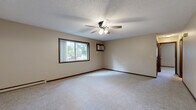 Located at 1641 Commerce Dr in North Mankato, MN, this single-floor unit offers three bedrooms, one bathroom, and a practical layout designed for comfortable everyday living. The generously sized primary bedroom is a standout feature of the space, offering ample room for furnishings and accented by a ceiling fan with light fixture, a textured ceiling, baseboard heating, a wall-mounted air conditioning unit, and a sliding window that brings in natural light. The additional bedrooms are carpeted and well-proportioned, each featuring windows that allow natural light to filter in, along with baseboard heating. The kitchen is efficiently arranged in a U-shaped layout with warm wood-toned cabinetry, light countertops, hardwood-style flooring, and white appliances including a refrigerator, electric range, built-in microwave, and dishwasher. The bathroom is clean and functional, featuring a full tub-shower combination with a handheld showerhead. Throughout the unit, neutral-toned walls, dark wood trim, and wall-to-wall carpeting in the living and bedroom areas contribute to a cohesive and understated aesthetic. Baseboard heating is present throughout the unit, complemented by ceiling fans in key rooms for year-round comfort.