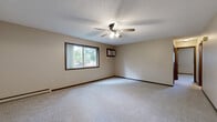 Located at 1641 Commerce Dr in North Mankato, MN, this single-floor unit offers three bedrooms, one bathroom, and a practical layout designed for comfortable everyday living. The generously sized primary bedroom is a standout feature of the space, offering ample room for furnishings and accented by a ceiling fan with light fixture, a textured ceiling, baseboard heating, a wall-mounted air conditioning unit, and a sliding window that brings in natural light. The additional bedrooms are carpeted and well-proportioned, each featuring windows that allow natural light to filter in, along with baseboard heating. The kitchen is efficiently arranged in a U-shaped layout with warm wood-toned cabinetry, light countertops, hardwood-style flooring, and white appliances including a refrigerator, electric range, built-in microwave, and dishwasher. The bathroom is clean and functional, featuring a full tub-shower combination with a handheld showerhead. Throughout the unit, neutral-toned walls, dark wood trim, and wall-to-wall carpeting in the living and bedroom areas contribute to a cohesive and understated aesthetic. Baseboard heating is present throughout the unit, complemented by ceiling fans in key rooms for year-round comfort.