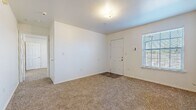 This single-floor unit offers a clean, functional layout designed for comfortable everyday living. The main living area greets occupants at the front entry, featuring soft carpeting underfoot, white walls, and a window fitted with blinds that allows natural light to filter in. A ceiling fan overhead helps maintain airflow throughout the space.

The galley-style kitchen is efficiently designed with light oak cabinetry lining both walls, offering generous storage. White laminate countertops provide ample workspace, while black appliances — including a range, refrigerator, and dishwasher — are neatly integrated into the layout. Warm wood-look flooring runs throughout the kitchen, adding visual warmth.

The living and dining area adjacent to the kitchen benefits from an open sightline, with a ceiling fan and wood-look flooring continuing the cohesive aesthetic. The bedrooms are carpeted and well-proportioned, each featuring windows with blinds that bring in natural light. One bedroom includes a ceiling fan for added comfort.

The bathroom is finished with wood-look flooring and includes a full-size soaking tub and shower combination with chrome fixtures, a toilet, and a vanity with oak cabinetry and a white countertop. Clean white walls and simple, practical finishes define the overall ambiance of this thoughtfully arranged space.