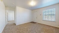 This single-floor unit offers a clean, functional layout designed for comfortable everyday living. The main living area greets occupants at the front entry, featuring soft carpeting underfoot, white walls, and a window fitted with blinds that allows natural light to filter in. A ceiling fan overhead helps maintain airflow throughout the space.

The galley-style kitchen is efficiently designed with light oak cabinetry lining both walls, offering generous storage. White laminate countertops provide ample workspace, while black appliances — including a range, refrigerator, and dishwasher — are neatly integrated into the layout. Warm wood-look flooring runs throughout the kitchen, adding visual warmth.

The living and dining area adjacent to the kitchen benefits from an open sightline, with a ceiling fan and wood-look flooring continuing the cohesive aesthetic. The bedrooms are carpeted and well-proportioned, each featuring windows with blinds that bring in natural light. One bedroom includes a ceiling fan for added comfort.

The bathroom is finished with wood-look flooring and includes a full-size soaking tub and shower combination with chrome fixtures, a toilet, and a vanity with oak cabinetry and a white countertop. Clean white walls and simple, practical finishes define the overall ambiance of this thoughtfully arranged space.