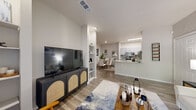 This single-floor residence offers a thoughtfully designed open-concept layout that seamlessly connects the living, dining, and kitchen areas. The living room features wood-look flooring, built-in shelving on either side of a media wall, and a large sliding glass door that floods the space with natural light and opens to a private patio with lush outdoor views. The adjacent dining area is a defined yet open space with wood-look flooring and a barn-style mirror accent, while the kitchen is equipped with gray shaker-style cabinetry, granite countertops, stainless steel appliances, and ample storage including a pantry closet. The primary bedroom is carpeted and generously sized, featuring large windows and an en-suite bathroom with a granite-topped vanity and a walk-in closet with wire shelving. The second bedroom is equally comfortable, also carpeted with natural light from a sizable window. The second bathroom mirrors the same quality finishes, including a granite vanity, gray cabinetry, and a full tub-shower combination. Throughout the residence, a neutral color palette and consistent finishes create a cohesive, modern aesthetic that is both functional and inviting.