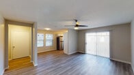 This single-floor residence offers a thoughtfully designed open-concept layout that seamlessly connects the living, dining, and kitchen areas. The living space features durable wood-look vinyl flooring, a ceiling fan with light, and a large sliding glass door with vertical blinds that floods the room with natural light and provides access to the outdoors. The kitchen is well-equipped with stainless steel appliances including a refrigerator, electric range, and built-in microwave. White shaker-style cabinetry, grey countertops, and a classic white subway tile backsplash complete the clean, modern aesthetic, while a window above the sink adds natural light. The bedrooms are comfortably sized, each featuring wood-look flooring, ceiling fans, and windows with outdoor views. At least one bedroom includes a built-in closet, and a nearby utility area houses an in-unit washer and dryer. The bathrooms are finished in a neutral palette with white cabinetry, dark countertops, and brushed nickel fixtures. One bathroom features an elongated vanity with ample storage and an adjacent tub-shower combination with tiled surround. Throughout the residence, consistent neutral-toned walls and modern finishes create a cohesive, move-in-ready atmosphere.