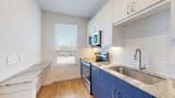 Located at 3900 Dacoma St in Houston, TX, this efficiently designed one-bedroom, one-bathroom unit offers a thoughtful layout across a single floor. Warm wood-look flooring flows throughout, creating a cohesive and inviting atmosphere.

The kitchen is a standout feature, showcasing bold navy lower cabinetry paired with crisp white upper cabinets and gold-toned hardware. A classic white subway tile backsplash, granite-style countertops, stainless steel appliances — including a range, microwave, and sink — and a bright window overlooking greenery complete the space.

The bedroom is a comfortable retreat, featuring a ceiling fan with light fixture and clean white walls. French-style glass doors open to a private balcony, flooding the room with natural light and providing outdoor views of surrounding trees.

The bathroom is finished with clean white subway tile lining the tub surround, brushed nickel fixtures, an illuminated vanity mirror, and navy cabinetry that ties cohesively to the kitchen's design palette.

A hallway connects the main living areas and includes a dedicated closet housing a stacked washer and dryer unit — a convenient in-unit laundry solution. An additional closet provides supplemental storage. The overall ambiance is modern, bright, and clean, with consistent finishes throughout.