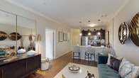 This thoughtfully designed single-floor residence offers a seamless blend of modern style and functional living. The open-concept layout connects the living, dining, and kitchen areas, creating an inviting flow throughout the space. Rich hardwood-style flooring runs through the main living areas, complemented by neutral-toned walls and elegant crown molding that add a refined architectural touch.

The kitchen is a standout feature, showcasing dark espresso cabinetry, granite countertops, a subway tile backsplash, and a full suite of stainless steel appliances. A granite-topped island with bar seating serves as both a functional workspace and a casual gathering spot, illuminated by stylish pendant lighting overhead.

The dedicated dining area offers an intimate setting, distinguished by a contemporary chandelier and crown molding details. The living room is generously proportioned and bathed in natural light from large windows with drapery accents.

The bedrooms are carpeted for comfort, with the primary bedroom featuring a ceiling fan and natural light from a window. The bathroom is finished with large-format tile flooring, a granite-topped dark vanity, and a walk-in shower, maintaining the cohesive design language found throughout the residence. Overall, the space exudes a contemporary yet welcoming ambiance.