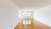 Located at 39 Latham Village Ln in Latham, New York, this two-bedroom, one-bathroom residence offers a practical and comfortable single-floor layout. Gleaming, polished hardwood floors extend throughout the main living areas and bedrooms, lending warmth and a sense of openness to the home. The spacious living room is bright and airy, featuring large multi-pane windows that invite natural light and provide views of the surrounding neighborhood. A pendant light fixture marks the transition into the dining area, which also benefits from generous windows overlooking the exterior. The kitchen is equipped with warm oak cabinetry, white appliances including a gas range and refrigerator, and tile flooring, offering a functional workspace. The generously sized primary bedroom features dual closets and polished hardwood floors, while the second bedroom includes windows with blinds that frame outdoor views. A connecting hallway provides easy access to all rooms. The full bathroom is finished with white tile walls accented by a dark border, a tub-shower combination, an oak vanity with a mirrored medicine cabinet, and tile flooring consistent with the kitchen. Clean white walls throughout create a neutral, move-in-ready canvas.