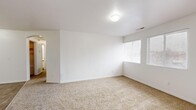 This well-organized single-floor residence offers a practical and comfortable layout across two bedrooms and one full bathroom. The kitchen is equipped with white cabinetry accented by warm wood trim, generous counter space, a double-basin sink, a dishwasher, and a full-size refrigerator, all set atop durable wood-look flooring that extends into the adjoining living area. The combined kitchen and living room area creates an open, functional hub for everyday living.

Both bedrooms feature plush wall-to-wall carpeting and windows fitted with horizontal blinds that allow for natural light while maintaining privacy. The spacious primary bedroom offers ample room and direct access to a well-organized closet complete with a hanging rod and built-in shelving units — ideal for maximizing storage. A second closet provides additional storage throughout the home.

The full bathroom is finished with wood-look flooring and includes a tub-shower combination with tiled surround, a toilet, and a single vanity with white cabinetry, gold-tone hardware, and a large mirror. A dedicated utility room and a connecting hallway round out the thoughtfully arranged floor plan. Throughout the home, crisp white walls, clean trim, and consistent finishes create a bright, neutral ambiance.