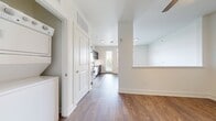 This 420-square-foot one-bedroom apartment in Savoye (unit E1, 2-556) showcases a thoughtful design that maximizes space efficiency. The open-concept floor plan creates a seamless flow between living areas, enhancing the sense of spaciousness. The kitchen is a highlight, boasting contemporary dark cabinetry, stainless steel appliances including a full-size refrigerator, range, microwave, and dishwasher. A subway tile backsplash adds a touch of elegance.

The bathroom features a modern vanity with ample storage, a large mirror, and a bathtub-shower combination with neutral tiling. Throughout the apartment, wood-look flooring adds warmth and continuity. The bedroom area, while not separately walled, offers space for a queen-sized bed and is brightened by large windows that also provide picturesque views.

A standout feature is the abundance of natural light, facilitated by expansive windows equipped with horizontal blinds for privacy control. A glass door leads to a small balcony or patio, further connecting the interior to the outdoors. The apartment's neutral color palette and clean lines create a canvas for personal style, making this compact space feel both inviting and contemporary.