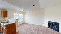 This single-floor residence offers a well-organized layout with distinct living, kitchen, bedroom, and bathroom areas. The living room is a notable highlight, featuring vaulted ceilings that enhance the sense of openness and a fireplace that serves as a functional focal point. Plush wall-to-wall carpeting runs throughout the main living areas and bedrooms, contributing to a warm and comfortable atmosphere.

The kitchen is designed for practicality, featuring warm wood-toned cabinetry, a white refrigerator, an electric range, and a peninsula that connects the kitchen to the adjacent living and dining areas. Multiple windows in the kitchen and dining space allow for ample natural light and views of the surrounding exterior. A walk-in pantry or storage closet is conveniently accessible from the kitchen area.

The bedrooms are generously proportioned, with the primary bedroom benefiting from vaulted ceilings, a ceiling fan, a large window, and direct access to a spacious walk-in closet equipped with wire shelving. Additional bedrooms are well-sized with natural light and closet access.

The bathrooms share a consistent design, each featuring a full tub-shower combination, a wood-vanity with a single sink, a wall mirror, and wood-look flooring, providing a clean and functional finish throughout.