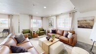 Located at 351 W 1600 N in Logan, Utah, this single-floor residence offers a thoughtfully designed layout that blends modern finishes with comfortable living. The interior features light-toned tile and wood-look flooring throughout, contributing to a bright and cohesive aesthetic.

The kitchen is a standout space, equipped with stainless steel appliances including a refrigerator, range, microwave, and dishwasher. Two-tone cabinetry pairs crisp white upper cabinets with dark lower cabinets, accented by white quartz countertops and a classic subway tile backsplash. A central island with bar seating provides additional prep and dining space, while a window offers views of the surrounding community.

The living room is generously sized and filled with natural light from multiple windows dressed with blinds and sheer curtains. Recessed lighting adds warmth overhead. A welcoming entryway features tile flooring and a charming arched built-in shelving unit. A secondary sitting area showcases a round wood-framed mirror and cozy seating nook.

Beyond the unit, residents enjoy access to impressive community amenities, including a large outdoor swimming pool surrounded by lounge chairs and shaded umbrellas, an outdoor grilling station with picnic seating, and a playground set within a landscaped green space — all set against the scenic backdrop of Utah's mountains.