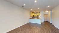 This single-floor residence offers a thoughtfully designed layout with a cohesive blend of practical features and comfortable living spaces. The open-concept living and dining area is finished with rich hardwood-style flooring and recessed lighting overhead, creating a bright, welcoming atmosphere. A sliding glass door brings in natural light and provides access to an outdoor area. The kitchen is defined by a peninsula with a warm-toned countertop that doubles as a breakfast bar. Light wood cabinetry extends to the upper walls, complemented by stainless steel appliances including a gas range, built-in microwave, refrigerator, and dishwasher. Tile flooring grounds the kitchen space cleanly. The bedrooms feature plush carpeting and windows dressed with blinds that filter natural light. One bedroom benefits from a ceiling fan and generous proportions, while a large walk-in closet with built-in shelving and hanging rods offers notable storage. The bathroom includes a wide vanity with light wood cabinetry and a full tub-shower combination with tile surround. A dedicated laundry area houses a full-size washer and dryer alongside overhead cabinetry, completing this functional and well-organized residence.