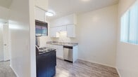 Located at 1328 E Hedrick Dr in Tucson, AZ, this single-story unit has been thoughtfully updated with contemporary finishes throughout. Wood-look flooring runs seamlessly across every room, creating a cohesive and clean aesthetic.

The kitchen is well-appointed with crisp white shaker cabinets, granite-style countertops, and a full suite of appliances including a stainless steel dishwasher, refrigerator, microwave, and an electric range. Ample upper and lower cabinet storage ensures generous workspace and organization. A second kitchen configuration visible in the images features a galley-style layout with cabinetry lining both walls for maximized efficiency.

The living area is open and bright, with large windows allowing natural light to fill the space. A sliding glass door connects the interior directly to a private outdoor area, enhancing the sense of openness. Ceiling fans are installed in multiple rooms, providing comfort suited to the Tucson climate.

The bedroom is spacious and well-lit, also equipped with a ceiling fan and offering easy access to adjacent spaces. The bathroom features a full tub-shower combination with white tile surround, a white vanity with granite-style countertop, and matching wood-look flooring for a uniform finish. The entry area is bright and welcoming, with sidelight windows framing the front door.