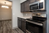 Located at 8044 Gleason Dr in Knoxville, Tennessee, this single-floor unit offers a clean, modern aesthetic throughout. The living area is bright and open, featuring light grey wood-look plank flooring and a sliding glass door that leads to a private balcony, allowing natural light to fill the space. A built-in closet with shelving is conveniently located nearby.

The kitchen is well-appointed with dark espresso cabinetry, light countertops, stainless steel appliances including a dishwasher and built-in microwave, and an electric range. An adjacent utility closet provides additional storage.

A central hallway connects the living areas to the bedrooms and bathroom. Each bedroom features the same durable wood-look flooring, a ceiling fan with light fixture, and a built-in closet. One bedroom benefits from dual windows, filling the room with abundant natural light and views of the surrounding greenery.

The bathroom is finished with neutral tile flooring, a vanity with dark cabinetry, and a separate water closet with a tub-shower combination. Throughout the unit, neutral grey walls, white trim, and consistent flooring create a cohesive and move-in ready environment suited for comfortable everyday living.