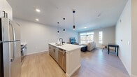 Located at 4607 Monona Dr in Monona, WI, this thoughtfully designed one-bedroom, one-bathroom residence offers a contemporary living experience across a single floor. The open-concept layout seamlessly connects the kitchen, dining, and living areas, maximizing the sense of space and flow throughout. The modern kitchen is a standout feature, centered around a large island with a quartz waterfall countertop and seating for multiple guests. Sleek gray cabinetry, stainless steel appliances including a gas range, microwave, and refrigerator, and matte black pendant lighting complete the polished look. Light wood-tone flooring runs throughout the main living areas, adding warmth to the neutral color palette. The living room is filled with natural light from expansive floor-to-ceiling windows and a sliding glass door that opens to a private balcony, offering views of the surrounding area. The bedroom features plush carpeting, a dedicated closet with double doors, and a calm, restful ambiance. The full bathroom is finished with a white vanity, quartz countertop, a combined tub and shower, and matte black fixtures. Additional conveniences include an in-unit laundry area and a dedicated closet for added storage.