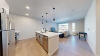 Located at 4607 Monona Dr in Monona, WI, this thoughtfully designed one-bedroom, one-bathroom residence offers a contemporary living experience across a single floor. The open-concept layout seamlessly connects the kitchen, dining, and living areas, maximizing the sense of space and flow throughout. The modern kitchen is a standout feature, centered around a large island with a quartz waterfall countertop and seating for multiple guests. Sleek gray cabinetry, stainless steel appliances including a gas range, microwave, and refrigerator, and matte black pendant lighting complete the polished look. Light wood-tone flooring runs throughout the main living areas, adding warmth to the neutral color palette. The living room is filled with natural light from expansive floor-to-ceiling windows and a sliding glass door that opens to a private balcony, offering views of the surrounding area. The bedroom features plush carpeting, a dedicated closet with double doors, and a calm, restful ambiance. The full bathroom is finished with a white vanity, quartz countertop, a combined tub and shower, and matte black fixtures. Additional conveniences include an in-unit laundry area and a dedicated closet for added storage.