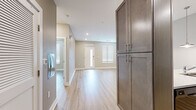 This single-floor unit is designed with a clean, contemporary aesthetic throughout. Light wood-tone luxury vinyl plank flooring runs consistently across the main living areas and bedrooms, creating a cohesive and warm feel. Neutral warm-gray and beige wall tones complement the bright white trim and recessed lighting found throughout the space.

The entryway features tall, dark-toned built-in cabinetry, providing substantial storage from the moment you step inside. A sidelight window beside the front door allows natural light to filter into the entry and adjacent living area, which is open and generously proportioned.

The kitchen is configured as a galley-style layout, equipped with gray shaker-style cabinetry, white countertops, a stainless steel sink, a dishwasher, and a full-size black stainless refrigerator. Pendant lighting adds a refined touch above the workspace. The kitchen opens toward the main living area, which benefits from recessed lighting and direct access to a closet and utility area.

Bedrooms are bright and well-sized, each featuring windows with blinds for natural light and privacy. The bathroom is finished with large-format tile flooring, a dual-sink dark wood vanity with a wide mirror, a soaking tub, and a separate tiled shower, offering a functional and polished retreat.