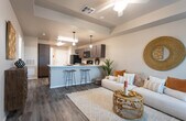 This single-story unit in Lubbock, Texas offers a thoughtfully designed open-concept layout that connects the living area and kitchen into one cohesive, functional space. The living room features a tray ceiling with a ceiling fan, warm neutral walls, and durable wood-style flooring that extends throughout the unit, creating a consistent, modern aesthetic.

The kitchen is generously sized and equipped with dark espresso-toned cabinetry, white countertops, and a full suite of black appliances including a refrigerator, range, microwave, and dishwasher. A peninsula with bar seating bridges the kitchen and living area, ideal for casual dining or entertaining. Pendant lighting adds a refined touch overhead.

The bedrooms are comfortably proportioned, with large windows that admit ample natural light. Ceiling fans provide additional climate control, and the wood-style flooring continues into each room. The bathrooms feature dark wood-finish vanities with white countertops, wood-style flooring, and upper cabinetry for added storage. One bathroom includes a shower-tub combination, while another offers a single-vanity configuration. The unit also includes in-unit laundry. Overall, the space presents a clean, contemporary design with warm, welcoming finishes.