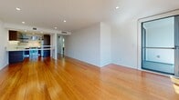 Located in the sought-after Marina del Rey neighborhood, this single-floor residence at 13900 Tahiti Way offers a thoughtfully designed open-concept layout that maximizes comfort and functionality. Warm bamboo hardwood flooring flows continuously throughout the main living areas, lending the space a clean, contemporary aesthetic complemented by crisp white walls and recessed lighting.

The expansive combined kitchen and living room serves as the heart of the home. The living area is anchored by a wall-mounted linear fireplace, creating a refined focal point, while large floor-to-ceiling windows and glass doors invite generous natural light and offer views of the surrounding Marina del Rey landscape. The kitchen features rich, dark-wood cabinetry with under-cabinet lighting, white countertops, a stainless steel sink, and a drawer-style dishwasher — all arranged in a streamlined galley configuration that opens to the living space via a raised breakfast bar.

The two bathrooms are finished with large-format neutral grey tiles, offering a calm, spa-like atmosphere. One bathroom includes a soaking tub set against full-height tiled walls with polished chrome fixtures. Frosted glass interior doors maintain privacy while preserving an open, light-filled feel throughout the hallway. A dedicated closet provides practical storage. The overall design balances modern minimalism with warm, natural materials.