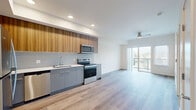 Located at 18807 8th Ave NE in Shoreline, WA, this thoughtfully designed one-bedroom, one-bathroom residence offers a contemporary living experience within a compact and efficient single-floor layout. Hardwood-style flooring flows seamlessly throughout the entire space, lending warmth and visual continuity to every room.

The open-concept kitchen and living area form the heart of the home. The kitchen is outfitted with stainless steel appliances — including a refrigerator, range, built-in microwave, and dishwasher — complemented by sleek gray lower cabinetry, warm wood-toned upper cabinets, light gray tile backsplash, and clean white countertops. Recessed lighting illuminates the kitchen, while a ceiling fan serves the living area. Sliding glass doors open directly onto a private balcony, filling the living space with natural light and offering pleasant outdoor views of the surrounding Shoreline neighborhood.

The bedroom is a well-proportioned retreat featuring a ceiling fan, a large window with views of the treeline, a sliding glass door to the balcony, and a double closet providing ample storage. The bathroom continues the modern aesthetic with light cabinetry, a white countertop vanity, and hardwood-style flooring. Clean white walls throughout maintain a bright, airy ambiance that enhances the overall sense of space.
