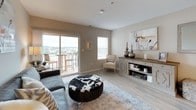 This single-floor residence is designed with a modern, open-concept layout that promotes a bright and airy atmosphere throughout. The kitchen is outfitted with stainless steel appliances, including a full-size refrigerator, range, and microwave, complemented by two-tone cabinetry featuring white upper cabinets and dark lower cabinets. Light wood-style flooring and recessed lighting enhance the space, while a peninsula with bar seating connects the kitchen to the main living area seamlessly.

The living room benefits from natural light and direct access to a private balcony through sliding glass doors, offering scenic outdoor views. The space accommodates a comfortable seating arrangement and additional storage furnishings.

Multiple bedrooms are present, each carpeted and featuring closet storage. The primary bedroom includes dual bifold closets and a large window with outdoor views. The additional bedrooms are well-sized, each with their own closet access and natural light.

Two bathrooms serve the residence. One features a contemporary floating vanity with a glass vessel sink and illuminated mirror, while the second offers a full tub-shower combination with crisp white finishes and tile flooring, providing a clean and functional layout throughout.