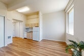 Located at 410 S Palm Dr in Novato, CA, this efficiently designed studio unit makes excellent use of its single-floor layout. The open-plan living, dining, and kitchen area forms the heart of the space, bathed in natural light from multiple windows fitted with vertical blinds. Exposed ceiling beams add a subtle architectural detail, complementing the warm, light-toned hardwood-style flooring that runs throughout the entire unit.

The compact kitchen is thoughtfully equipped with light maple cabinetry, a white refrigerator, a stove, and a stainless steel sink — all neatly tucked into a defined alcove that keeps the living area feeling open and uncluttered. Two sliding-door closets provide practical storage solutions within the main living space, maintaining the clean, minimalist aesthetic of the unit.

A hallway connects the main area to the bathroom, which features a single-sink vanity with light maple cabinetry, a large mirror, a toilet, and a shower/tub combination with grab bar accessibility. The neutral warm-beige palette carried throughout creates a cohesive and calm ambiance. Situated in Novato's Hamilton neighborhood, this unit offers a straightforward, functional layout suited to efficient, comfortable everyday living.