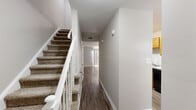 Located at 3219 Shamrock Dr in Charlotte, NC, this two-story home offers three bedrooms and three bathrooms across two well-organized floors. The main level features a bright, open living room with hardwood-style flooring that allows natural light to flow freely throughout the space. The galley-style kitchen is equipped with warm honey-toned wood cabinetry, light granite-style countertops, a double basin sink, a dishwasher, and a black appliance suite including a range and refrigerator. A window above the kitchen area brings in natural light, enhancing the functional layout. A carpeted staircase with white balusters and a wood handrail connects the two floors. The upper level houses the bedrooms, each finished with plush carpet and neutral-toned walls. The spacious primary bedroom includes a dedicated closet. The additional bedrooms are well-proportioned with access to natural light via blinds-fitted windows. The three bathrooms feature white vanities with granite-style countertops and wood-look flooring. Two closets provide additional storage throughout. The home's clean, neutral palette and consistent finishes create a cohesive and move-in-ready atmosphere throughout.