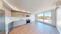 Located on Stone Way N in Seattle's vibrant Wallingford neighborhood, this modern 2-bedroom, 2-bathroom residence offers a thoughtfully designed single-level layout. Light wood-tone flooring flows consistently throughout, complementing the clean, contemporary aesthetic found in every room.

The open-concept kitchen is a standout feature, outfitted with flat-front cabinetry in a warm wood finish, white subway tile backsplash, sleek quartz countertops, and a full suite of stainless steel appliances including a refrigerator, range, microwave, and dishwasher. The kitchen opens directly to the living area, which is bathed in natural light from a large floor-to-ceiling window offering views of the surrounding Seattle skyline and treetops.

Both bedrooms are bright and airy, with large windows that frame outdoor views. The primary bedroom connects to a dedicated bathroom for added convenience. A second full bathroom serves the remaining bedroom and guests, each bathroom featuring modern vanities with quartz countertops, wood-toned cabinetry, and clean tile finishes.

Three hallways connect the spaces efficiently, and two closets — including a spacious walk-in — provide ample storage. Recessed lighting throughout adds to the polished, move-in-ready feel of this well-appointed Seattle residence.
