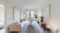 Located at 1401 Pennsylvania Ave SE in Washington, DC's Capitol Hill neighborhood, this single-floor residence offers a thoughtfully designed contemporary interior with a clean, neutral palette throughout. The open-concept living area is anchored by large floor-to-ceiling windows that frame views of the surrounding neighborhood, filling the space with abundant natural light. Light wood-tone flooring flows seamlessly through the living and dining areas, enhancing the airy, modern ambiance. The kitchen is outfitted with sleek white upper cabinetry, warm wood-toned lower cabinets, white quartz countertops, and stainless steel appliances including a range, dishwasher, and microwave — a functional and stylish space for everyday living. The bedroom features generous proportions, a large picture window with neighborhood views, and light-toned walls that contribute to a calm, restful atmosphere. The bathroom is finished with a wood-grain vanity, white quartz countertop, a full mirror, and light tile flooring, maintaining the consistent modern aesthetic found throughout the home. Overall, the residence combines contemporary design, practical finishes, and natural light to create a comfortable and welcoming living environment in the heart of Washington, DC.