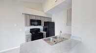 Located at 4075 Alkire Glen Way in Columbus, Ohio, this single-floor residence offers a clean, contemporary design with thoughtfully selected finishes throughout. The kitchen is a standout feature, showcasing gray shaker-style cabinetry paired with light granite-look countertops that provide ample prep space. A classic white subway tile backsplash adds a timeless touch, while black appliances — including a range, over-the-range microwave, and full-size refrigerator — deliver a cohesive, modern aesthetic. The double-basin stainless steel sink is fitted with a brushed nickel faucet, combining style with practicality. The kitchen benefits from notably high ceilings, creating an open and airy atmosphere that enhances the sense of space. The light, neutral wall tones throughout contribute to a bright and welcoming environment. The overall design reflects a balance of functionality and modern style, making it well-suited for everyday living. The single-floor layout ensures convenient accessibility, with a logical flow between living areas. This residence at Alkire Glen Way presents a well-appointed interior with quality finishes that are both attractive and durable.