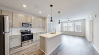 Located at 1401 Dixie Hwy in Covington, Kentucky, this single-floor residence offers a thoughtfully designed open-concept layout with contemporary finishes throughout. The kitchen serves as a central focal point, featuring light wood-grain cabinetry, white subway tile backsplash, stainless steel appliances including a refrigerator, range, and built-in microwave, and a large center island with a built-in sink and light countertops. Stylish pendant lighting hangs above the island, complementing the recessed ceiling lights. Wood-style flooring runs through the kitchen and connects seamlessly to the living area, which receives natural light through large windows fitted with blinds.

Multiple bedrooms feature plush wall-to-wall carpeting and individual windows that bring in natural light. One bedroom includes access to a walk-in closet with wire shelving and an adjacent full bathroom with a tub-shower combination and tile surround. A second full bathroom offers a dual-sink vanity with matching light cabinetry, a large framed mirror, and a tiled walk-in shower. A dedicated laundry area accommodates a full-size washer and dryer, adding everyday convenience to this well-appointed residence.