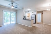 This single-floor residence offers a thoughtfully designed open-concept layout that seamlessly connects the living area and kitchen. The living room is finished with plush wall-to-wall carpeting and features crown molding, a ceiling fan with light fixture, and a sliding glass door that opens to a private balcony overlooking lush greenery, filling the space with natural light. Adjacent to the living area, a dedicated dining space is accented by a chandelier, adding a touch of elegance.

The kitchen is well-equipped with stainless steel appliances, including a refrigerator, electric range, and over-the-range microwave. White cabinetry with brushed nickel hardware pairs with dark countertops for a clean, modern contrast. A double-basin stainless steel sink sits beneath a window, and a breakfast bar peninsula provides additional counter space and casual seating.

The bathroom features a full tub-shower combination with white tile surround and brushed nickel fixtures, complemented by wood-look flooring for a warm finish. A generously sized walk-in closet offers multiple wire shelving levels and hanging rods, providing ample storage. Throughout the home, neutral tones and consistent finishes create a cohesive and inviting atmosphere.