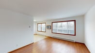This single-floor home at 4134 Laramie Ln in Rockford, Illinois offers a clean, functional layout with a consistent design language throughout. The main living area is spacious and filled with natural light, courtesy of large windows with warm wood trim that frame views of the surrounding neighborhood. Hardwood flooring extends throughout the living and bedroom spaces, adding warmth and continuity to the interior. Baseboard heating runs along the walls, and a wall-mounted air conditioning unit ensures year-round climate comfort.

The bedrooms are well-proportioned, featuring the same hardwood flooring, white walls, and wood-trimmed windows and doors that define the home's aesthetic. The bathroom is neatly appointed with gray cabinetry, a white countertop vanity, a large mirror with overhead lighting, and tile flooring.

The kitchen is efficiently designed with gray shaker-style cabinetry, light countertops, and tile flooring. It is equipped with a full suite of appliances including a refrigerator, electric range, and stainless steel dishwasher. A stacked washer and dryer unit is conveniently located within the kitchen area, offering in-unit laundry. The overall layout is practical and well-organized, making this a comfortable and move-in ready home.