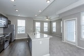 This single-floor residence offers a thoughtfully designed open-concept layout that seamlessly connects the kitchen and living areas. The kitchen is a functional centerpiece, featuring dark espresso cabinetry, stainless steel appliances including a refrigerator, range, and microwave, a white subway tile backsplash, and a large granite-topped island with an integrated sink. Wood-look hard flooring grounds the kitchen space, while recessed lighting and abundant natural light from multiple windows enhance the bright, airy atmosphere.

The living area extends naturally from the kitchen, finished with plush neutral carpeting and a ceiling fan. Multiple bedrooms continue the carpeted aesthetic, each offering generous proportions, tray or standard ceilings, ceiling fans, and ample natural light. Several bedrooms include closets with built-in shelving and hanging rods for organized storage.

The bathrooms are well-appointed, with one featuring a granite-topped dark vanity, wood-look flooring, and a large mirror, while a second includes a full tub-shower combination with tiled surround and dark overhead cabinetry. A dedicated laundry room with full-size washer and dryer connections and overhead shelving adds everyday convenience throughout this cohesive, move-in-ready residence.