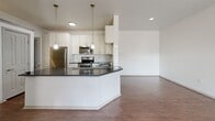 This 1,180-square-foot apartment at 4699 Kittredge Street in Denver, Colorado offers four bedrooms and three bathrooms across a single floor. The open-concept kitchen and living area serves as the heart of the unit, featuring white shaker cabinetry, dark granite countertops, a white subway tile backsplash, stainless steel appliances including a refrigerator, range, and microwave, and pendant lighting over a wraparound breakfast bar. Rich hardwood-style flooring runs throughout the main living areas, complementing the bright, neutral color palette. The living room benefits from natural light through French doors with transom windows. The primary bedroom spans 190 square feet and includes a walk-in closet with built-in shelving and hanging rods. The bathrooms are finished with gray subway tile, dark granite vanity tops, white cabinetry, and framed mirrors with modern lighting fixtures. Additional bedrooms are carpeted and equipped with ceiling fans and ample natural light from large windows with outdoor views. A dedicated hallway connects the rooms efficiently, and the overall layout is well-organized for comfortable everyday living.