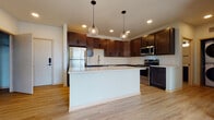 Located at 6414 Bridge Rd in Monona, Wisconsin, this single-floor unit offers a thoughtfully designed layout with modern finishes throughout. The kitchen serves as a central highlight, showcasing rich dark-stained shaker-style cabinetry that extends to the ceiling, providing generous storage. A classic white subway tile backsplash contrasts elegantly with the dark cabinetry, while light-toned countertops add brightness to the space. A central island with a clean white finish offers additional prep space and casual seating potential, illuminated overhead by two globe pendant lights. Stainless steel appliances, including a refrigerator, range, microwave, and dishwasher, complete the kitchen's functional and cohesive aesthetic.

Light hardwood-style flooring runs consistently throughout the living areas and bedrooms, lending warmth and visual continuity. The living spaces are bright and open, benefiting from recessed lighting and ceiling fans. Bedrooms feature large windows that invite natural light and offer outdoor views, complemented by roller shades for privacy. The bathroom is finished with a walk-in shower, white vanity with light countertops, tile flooring, matte black hardware accents, and built-in open shelving for convenient storage.