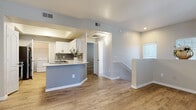 Located at 10 W Minnezona Ave in Phoenix, Arizona, this two-story home combines modern updates with a functional, well-designed layout. The open-concept main level features warm wood-look flooring that flows seamlessly from the living area into the kitchen. The kitchen is a standout, appointed with white shaker cabinetry, grey lower accents, a grey tile backsplash, quartz countertops, stainless steel appliances including a refrigerator, range, and over-the-range microwave, and a large undermount sink set into a peninsula that provides added prep and seating space. A dedicated laundry area with a washer is conveniently accessible directly from the kitchen. The living area is bright and airy, benefiting from multiple windows dressed with blinds and a ceiling fan overhead. A staircase connects the floors, leading to the upper level where carpeted bedrooms offer a comfortable retreat. Each bedroom features neutral tones, a ceiling fan, and a window for natural light. The bathrooms are clean and modern, each equipped with a tub-shower combination and wood-look flooring. One bathroom includes a frosted glass window for added natural light and privacy. The overall aesthetic is fresh and cohesive throughout.
