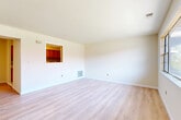 This well-appointed 1-bedroom, 1-bathroom residence in Sayreville, NJ offers a thoughtfully laid-out single-floor plan with a clean, modern aesthetic throughout. Light-toned hardwood flooring flows seamlessly across the spacious living room, bedroom, and connecting areas, creating a cohesive and airy feel. The living room is generously proportioned, featuring a distinctive pass-through window that connects to the kitchen, allowing natural light and an open sense of flow between the two spaces. Large windows frame pleasant outdoor views of blooming trees, filling both the living room and bedroom with abundant natural light. The kitchen is equipped with warm honey-toned wood cabinetry, marble-look countertops, a stainless steel sink, a dishwasher, and an eye-catching mosaic tile backsplash in earthy tones that adds a stylish accent. The bedroom is a comfortable size, offering two closets with white panel doors — providing ample storage. The bathroom features a full soaking tub with a shower, elegantly clad in large-format marble-look tile in white and grey tones, lending a clean and sophisticated finish. Neutral wall tones throughout the residence contribute to a bright, inviting ambiance.