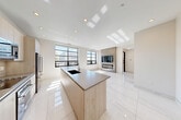 Located at 229 Waterman St in Providence's vibrant East Side neighborhood, this thoughtfully designed one-bedroom, one-bathroom residence offers a clean, contemporary aesthetic across a single well-organized floor. Large black-framed windows flood the open living and kitchen area with natural light and frame views of the surrounding Providence skyline and greenery.

The kitchen is a standout feature, showcasing light wood cabinetry, a subway tile backsplash, stainless steel appliances including a full-size refrigerator and built-in microwave, and a central island with a crisp white countertop — ideal for both cooking and casual dining. The open-plan living area flows seamlessly from the kitchen, featuring large-format polished tile flooring, recessed lighting, and a sleek built-in media wall with a modern fireplace.

The bedroom is generously proportioned, bathed in natural light through dual black-framed windows, and finished with the same polished tile flooring that carries throughout the unit. The bathroom is spa-inspired, featuring warm stone-look tile walls, a frameless glass walk-in shower with a ceiling-mounted rain showerhead, a floating wood-toned vanity, and warm beige floor tiles. The hallway connects each space efficiently, accented by rich dark wood interior doors with chrome hardware, adding a refined contrast to the bright, neutral palette throughout.