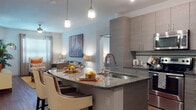 Located at 9926 Grande Lakes Blvd in Orlando, FL, this well-appointed two-bedroom, two-bathroom residence offers a thoughtfully designed single-level layout with modern finishes throughout. The open-concept kitchen is a standout feature, showcasing sleek flat-front cabinetry in a warm gray tone, granite countertops, a spacious island with bar seating, stainless steel appliances, a tile backsplash, and pendant lighting that adds a contemporary flair. The kitchen flows seamlessly into the living area, which features rich hardwood-style flooring, a ceiling fan, and large windows that invite natural light. Both bedrooms are generously sized with plush carpeting, ceiling fans, ample natural light from well-placed windows, and walk-in closets for added storage. The two bathrooms are finished with granite-topped vanities, wood-style flooring, and clean subway tile surrounds in the tub-shower combinations. Neutral tones and consistent design elements create a cohesive and inviting ambiance throughout the home, while the overall layout maximizes functionality and comfort, making this Orlando residence a refined and practical living space.