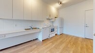 Located at 2471 Gately Avenue in Port Coquitlam, BC, this one-bedroom, one-bathroom unit offers a thoughtfully designed layout across a single floor. Light hardwood flooring flows consistently throughout the space, lending warmth and continuity to every room.

The kitchen is efficiently arranged with full-height white cabinetry featuring gold-toned hardware, providing generous storage from counter to ceiling. White appliances — including a refrigerator, electric range, dishwasher, and range hood — are neatly integrated into the layout. A stainless steel sink sits along the countertop, and track lighting above ensures the area is well-lit.

The bedroom is a compact yet functional space, benefiting from a large window that brings in natural light and offers views of the surrounding neighbourhood. A baseboard heater provides in-suite climate control, and the clean white walls create a bright, open atmosphere.

The bathroom is designed with accessibility in mind, featuring stainless steel grab bars and a roll-in shower with a fold-down seat, making it suitable for a wide range of occupants. The consistent light flooring and white walls carry through here as well.

Overall, this unit presents a clean, modern aesthetic with practical, accessible features throughout.