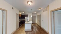 This single-story residence at 404 S Mary St in Arlington, Texas offers a well-designed, open-concept layout finished with consistent hardwood-style flooring throughout. The main living and kitchen area forms the heart of the unit, where a central island with a granite countertop and undermount stainless steel sink serves as both a functional workspace and a visual focal point. Pendant lighting above the island complements the track lighting positioned over the kitchen, illuminating rich, dark espresso cabinetry paired with a decorative mosaic tile backsplash. Stainless steel appliances, including a refrigerator, range, and microwave, complete the kitchen's polished aesthetic.

The open layout allows the living area to flow naturally from the kitchen, creating a cohesive and spacious common area. Flush-mount ceiling fixtures provide ambient lighting throughout. The bedrooms each feature ceiling fans with light kits and windows fitted with blinds that bring in natural light. One bedroom includes a closet with sliding doors.

Two bathrooms serve the unit: one features a soaking tub with full tile surround and dark vanity with granite countertop, while the second offers a glass-enclosed walk-in shower with tile walls, a built-in niche shelving unit, and a matching granite-topped vanity.