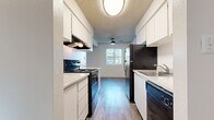 This 2-bedroom, 2-bathroom single-floor unit offers a practical and well-organized layout designed to maximize usable living space. The galley-style kitchen runs along a central corridor, featuring white cabinetry with ample upper and lower storage, light granite-style countertops, black appliances including a refrigerator, electric range, and dishwasher, and wood-style plank flooring that extends throughout the unit. A window at the end of the kitchen allows natural light to filter in, and a ceiling fan adds comfort to the adjacent living area.

The two bedrooms are comfortably sized, with the primary bedroom offering generous square footage. Both rooms feature neutral white walls, wood-style flooring, and textured ceilings, creating a clean and versatile backdrop. Sliding closet doors in at least one bedroom provide accessible built-in storage.

The two bathrooms are finished consistently, each equipped with a white vanity, granite-style countertop, mirrored medicine cabinet, and wood-style flooring. The full bathroom includes a tub-shower combo, while the second bathroom functions as a half or three-quarter bath. Throughout the unit, the consistent use of light tones, wood-style flooring, and white finishes creates a cohesive, move-in-ready aesthetic.