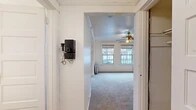 Located at 1025 SW 11th Ave in Portland, Oregon, this single-floor unit blends classic architectural character with practical functionality. The layout, as revealed through the floor plan, comprises a series of interconnected rooms that flow logically from an entry hallway through to the living areas, bedroom spaces, kitchen, and bathroom.

The entry hallway features white-painted walls with a vintage wall-mounted telephone, adding a distinctive period charm. Crown molding is present throughout, reinforcing the building's traditional architectural style. A wide archway leads into the main living area, which is carpeted and brightened by a pair of double-hung windows overlooking the street. A ceiling fan with a light fixture is centrally positioned overhead, and a cast-iron radiator beneath the windows provides supplemental heating.

The bedroom areas are carpeted and finished with white walls and panel-style doors fitted with brass hardware. Crown molding continues throughout, maintaining a cohesive aesthetic. Each room connects conveniently to adjacent spaces.

The kitchen features tile flooring, warm-toned upper walls with a chair-rail detail, and includes a freestanding white gas range alongside a refrigerator.

The bathroom is finished with tile flooring, white walls accented by a horizontal molding detail, a recessed medicine cabinet mirror, and a classic clawfoot-style bathtub with chrome fixtures, contributing to the unit's period character.