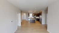 Located at 16533 E 49th Ave in Denver, Colorado, this modern single-floor residence offers a well-designed layout with contemporary finishes throughout. The open-concept living and kitchen area serves as the heart of the home, featuring light hardwood-style flooring that enhances the bright, airy atmosphere. The kitchen is a standout, outfitted with rich dark cabinetry, crisp white quartz countertops, a subway tile backsplash, and a full suite of stainless steel appliances including a French door refrigerator, electric range, built-in microwave, and dishwasher. A central island with pendant lighting provides additional prep space and casual seating. In-unit stacked laundry is conveniently accessible from the kitchen area. The bedrooms are carpeted for comfort, each receiving natural light through large windows with blinds. One bedroom features direct access to a walk-in closet and an adjacent bathroom. The bathroom is finished with dark wood-toned cabinetry, a white quartz vanity, framed mirror, and a soaking tub with a tiled shower surround. Neutral wall tones and clean architectural lines create a cohesive, modern ambiance throughout the entire space.