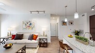 This single-story residence offers a smartly designed open-concept layout that maximizes every square foot of living space. The living room serves as the heart of the home, featuring wood-style plank flooring, a ceiling fan, and track lighting. Large windows flood the room with natural light and provide views to the outdoors, while a sliding door offers additional brightness and access. A dedicated dining area sits adjacent to the living space, making entertaining seamless.

The kitchen is equipped with dark espresso cabinetry extending to the ceiling for ample storage, stainless steel appliances including a refrigerator, range, and microwave, a subway tile backsplash, and a granite-topped peninsula that doubles as a breakfast bar with pendant lighting above.

The bedroom is generously sized, featuring plush carpet, a ceiling fan, and large windows that invite natural light. A walk-in closet provides substantial storage. The full bathroom includes a tiled soaking tub and shower combination, rich dark wood cabinetry, and clean, neutral finishes. An in-unit laundry area adds everyday convenience. Throughout the residence, a bright, neutral color palette and cohesive modern design create a warm and welcoming ambiance.