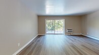 Located at 300 Glen Meadow Rd in Franklin, MA, this 2-bedroom, 1-bathroom residence offers a well-designed single-floor layout with consistent light wood flooring throughout, creating a warm and cohesive aesthetic. The kitchen is outfitted with crisp white shaker cabinets, dark countertops, a subway tile backsplash, and a stainless steel sink, with a pass-through window that connects it seamlessly to the living area. The combined kitchen and living room provides a comfortable, open feel with access to a sliding glass door that opens to a balcony overlooking lush, mature trees — bringing natural light and peaceful outdoor views into the space. The primary bedroom is generously sized, featuring three windows that invite ample natural light, and is served by baseboard heating. The second bedroom is bright and cozy with its own window and closet access. Both bedrooms continue the light wood flooring found throughout. The full bathroom is a standout, showcasing a tub-shower combination with striking marble-patterned surround panels and a sliding glass door, paired with clean white fixtures. Neutral warm-tone walls and white trim throughout lend the home a fresh, move-in ready character well-suited to a variety of lifestyles.
