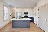Located at 277 Clifton St SE in Atlanta, GA, this contemporary three-story home offers five bedrooms and four bathrooms across a well-designed layout. Light hardwood flooring flows consistently throughout all levels, creating a cohesive and modern aesthetic.

The main level features an open-concept kitchen and living area. The kitchen is a standout, showcasing a two-tone design with crisp white upper cabinetry, slate-gray lower cabinets, and a large center island with a white quartz countertop and built-in sink. Stainless steel appliances, including a range and built-in microwave, complete the modern culinary space. Recessed lighting and large windows invite natural light into the area.

The bedrooms are bright and airy, each benefiting from multiple windows with views of surrounding greenery. Ceiling fans are present in several rooms, and the clean white walls provide a neutral, versatile canvas. The primary bedroom is a generously sized retreat with ample natural light.

The four bathrooms are finished with a consistent modern palette, featuring wood-toned vanities with white quartz countertops and matte black hardware. Bathrooms include both walk-in glass-enclosed showers and full tub-shower combinations. Two dedicated closets and a hallway add practical storage and circulation throughout the home.