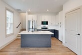 Located at 277 Clifton St SE in Atlanta, GA, this contemporary three-story home offers five bedrooms and four bathrooms across a well-designed layout. Light hardwood flooring flows consistently throughout all levels, creating a cohesive and modern aesthetic.

The main level features an open-concept kitchen and living area. The kitchen is a standout, showcasing a two-tone design with crisp white upper cabinetry, slate-gray lower cabinets, and a large center island with a white quartz countertop and built-in sink. Stainless steel appliances, including a range and built-in microwave, complete the modern culinary space. Recessed lighting and large windows invite natural light into the area.

The bedrooms are bright and airy, each benefiting from multiple windows with views of surrounding greenery. Ceiling fans are present in several rooms, and the clean white walls provide a neutral, versatile canvas. The primary bedroom is a generously sized retreat with ample natural light.

The four bathrooms are finished with a consistent modern palette, featuring wood-toned vanities with white quartz countertops and matte black hardware. Bathrooms include both walk-in glass-enclosed showers and full tub-shower combinations. Two dedicated closets and a hallway add practical storage and circulation throughout the home.